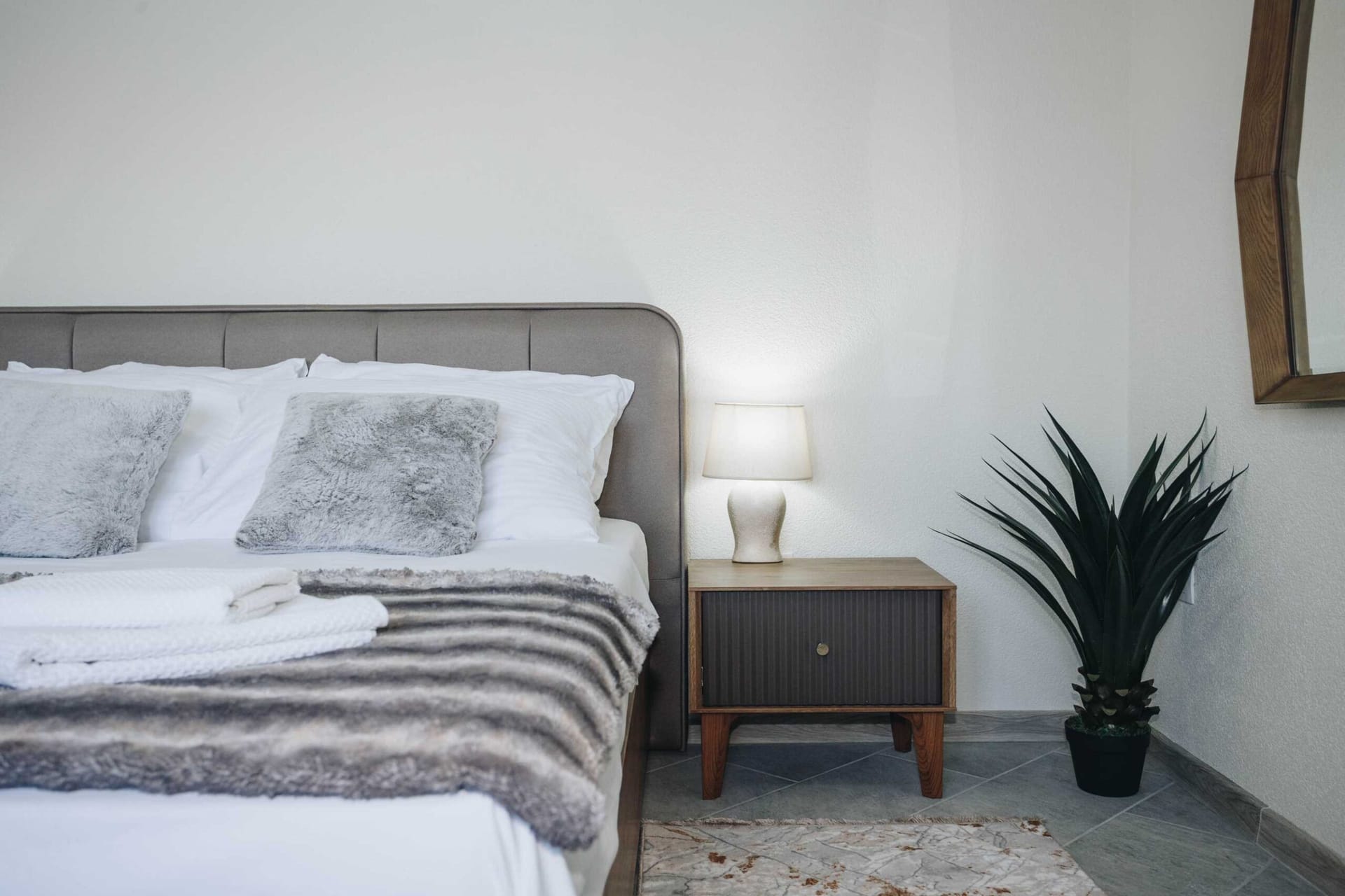 Cozy bedroom in a villa in Krašići, Montenegro: a double bed, a stylish nightstand, a lamp, and decor in the interior.