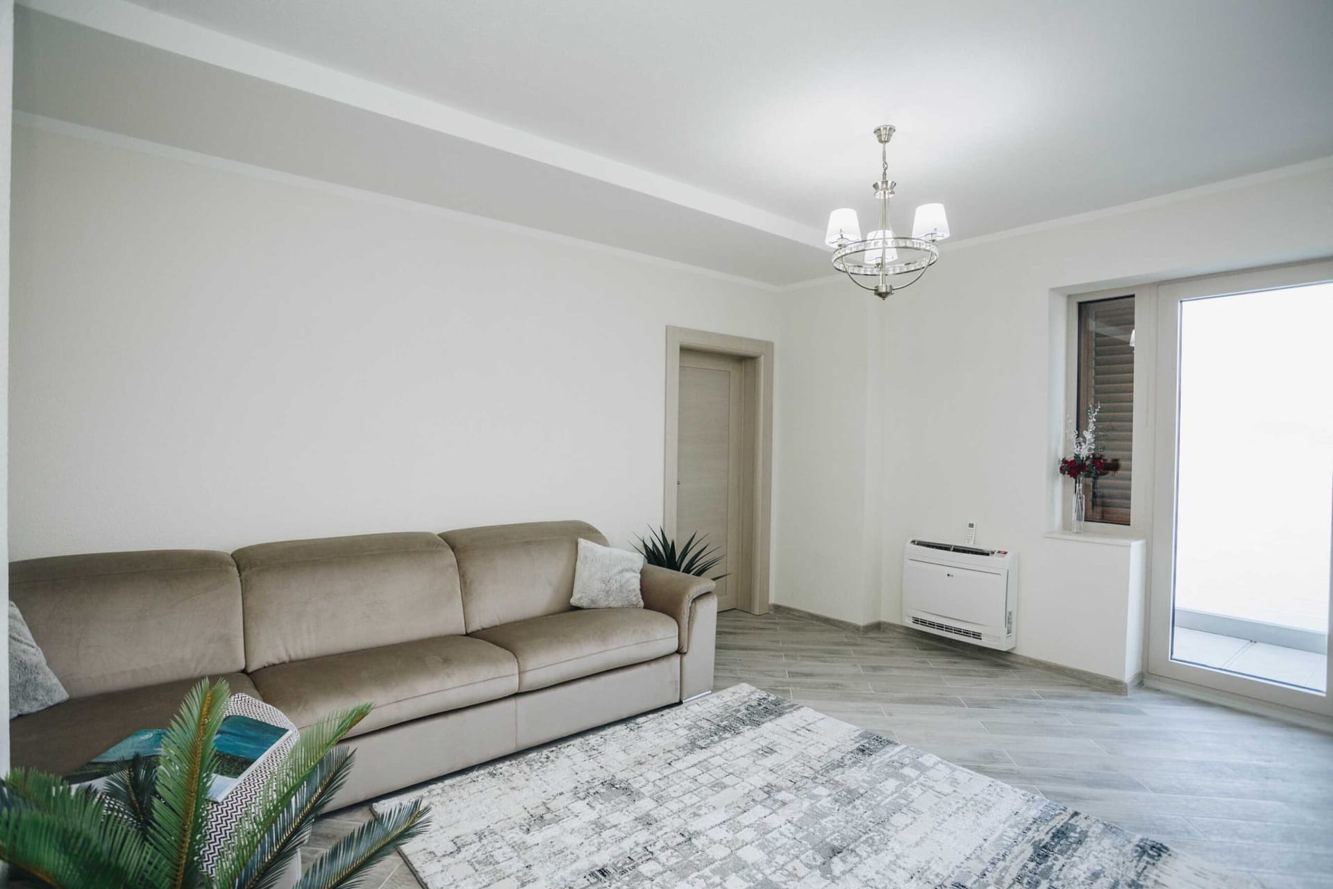 Bright living room with a beige sofa, rug, and access to the terrace in a villa in Krašići, Montenegro.