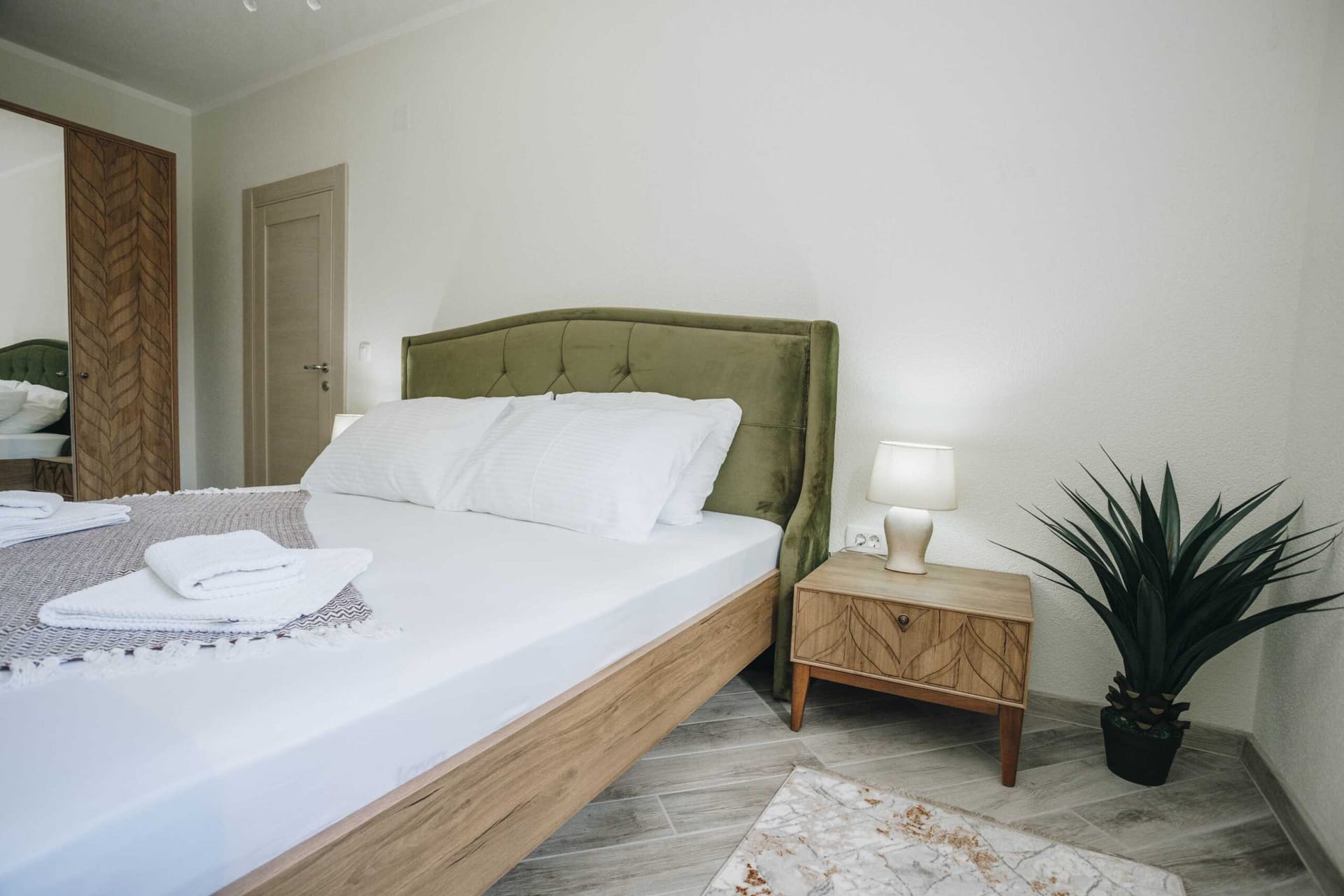 Bedroom with a double bed, green headboard, and wooden nightstand in a villa in Krašići, Montenegro.