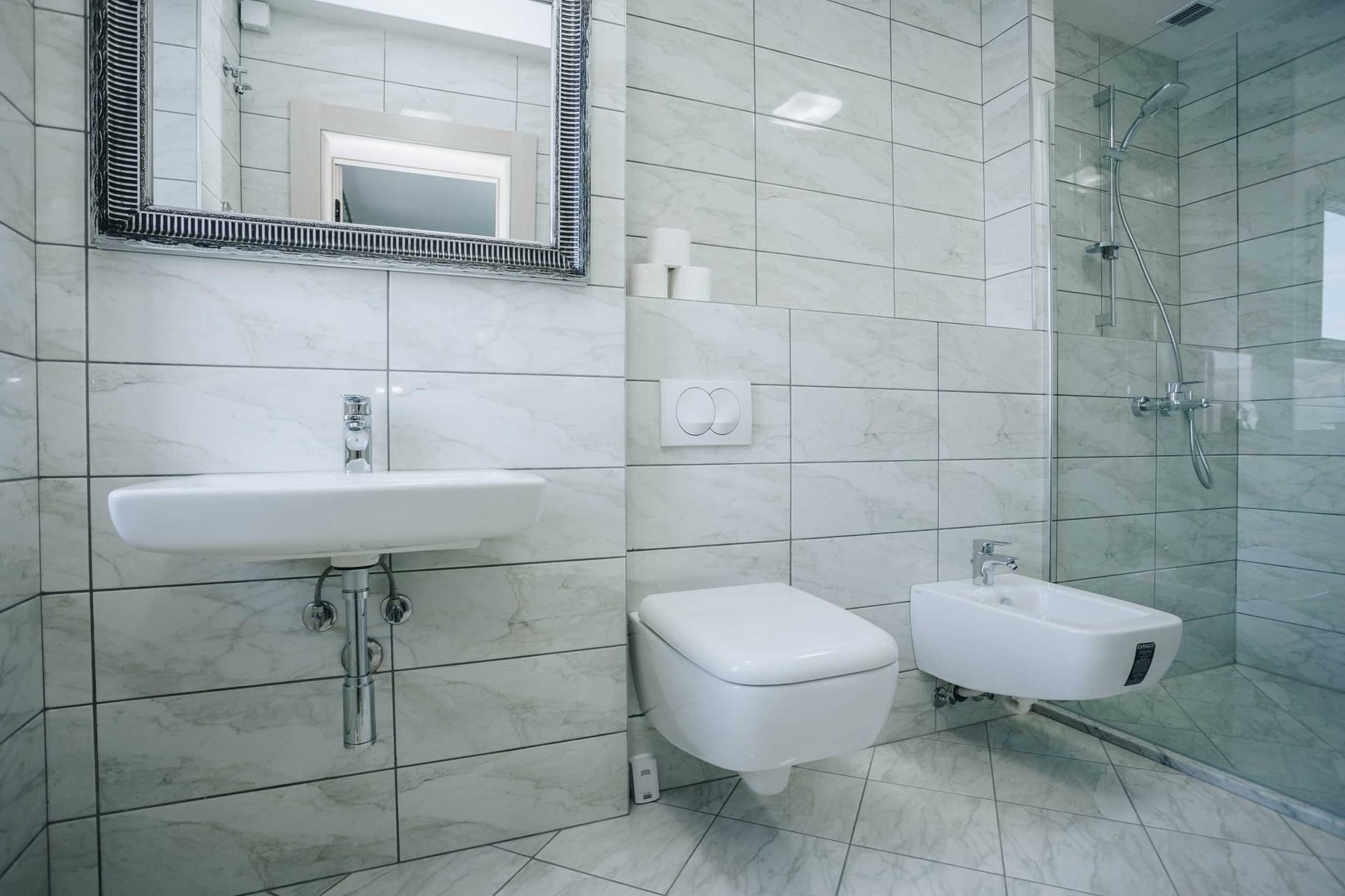 Modern bathroom with shower cabin and bidet in a villa in Krašići, Montenegro: marble-look tile finish.