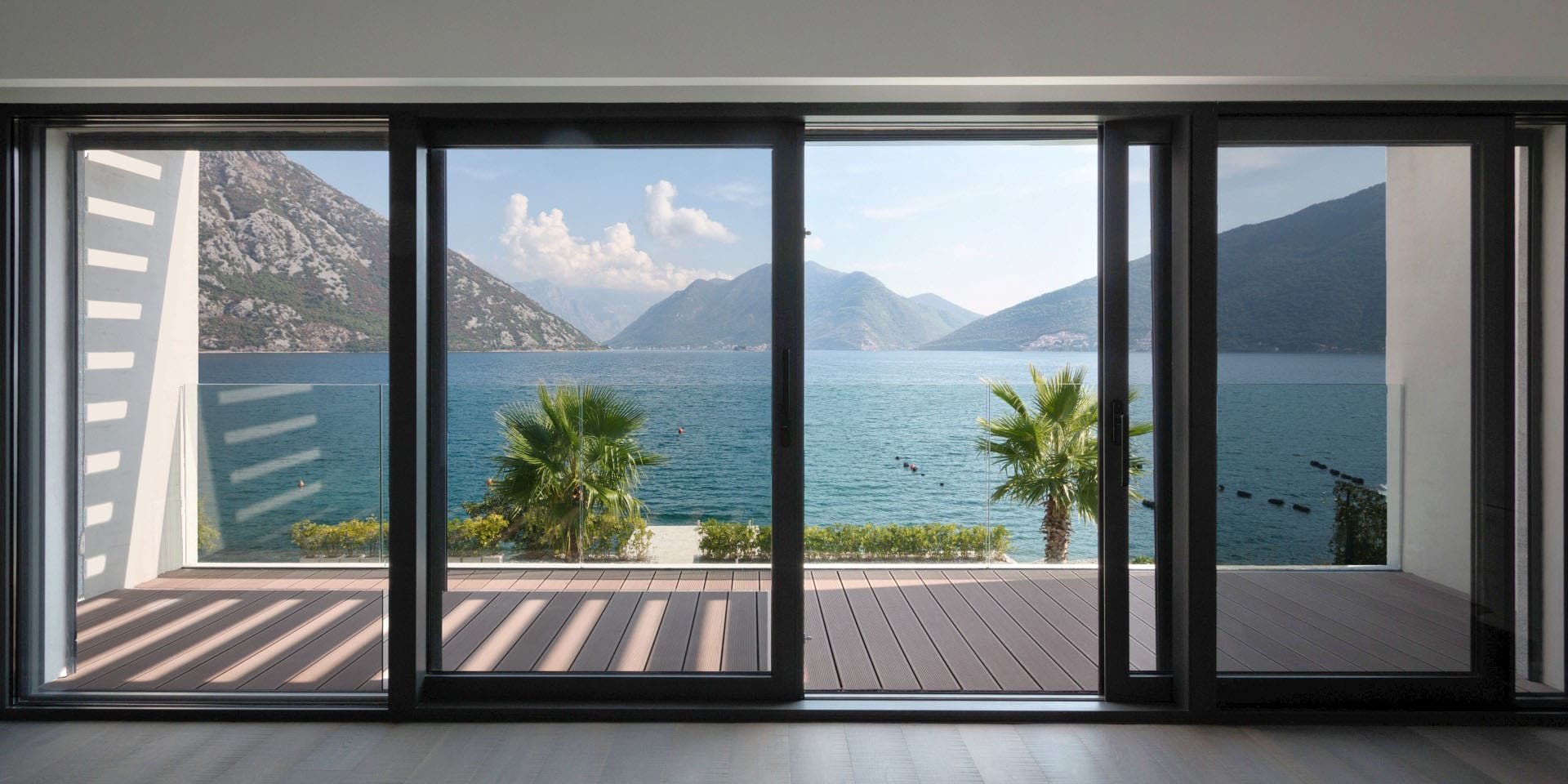 Panoramic sea and mountain view from the villa living room in Strp, Montenegro, with access to a terrace with wooden decking.