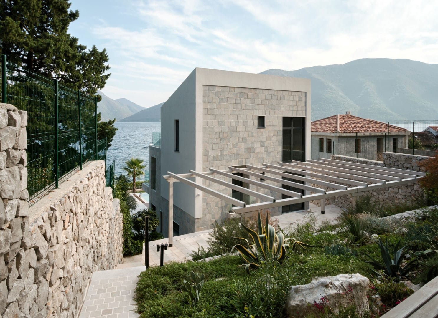 Modern stone villa with a terrace and sea view in the village of Strp, Montenegro, surrounded by a landscaped garden.