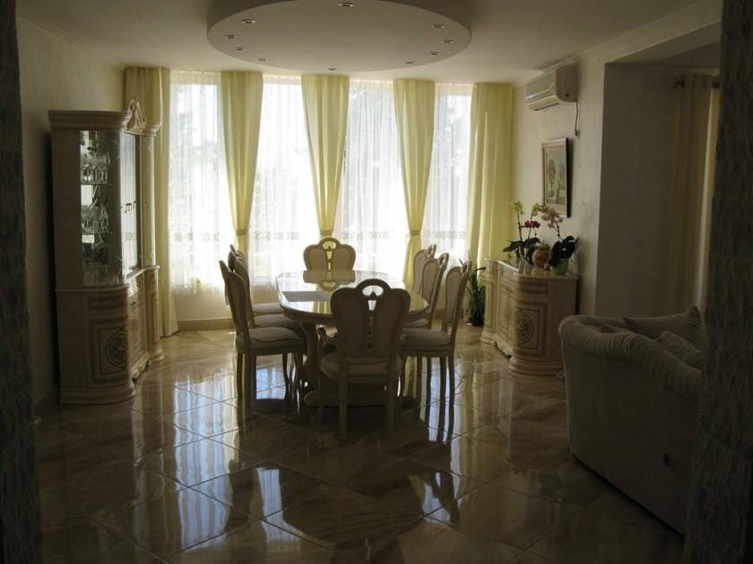 Living room with dining area in a villa in Shushan, Montenegro: classic furniture, marble floor, and panoramic windows.