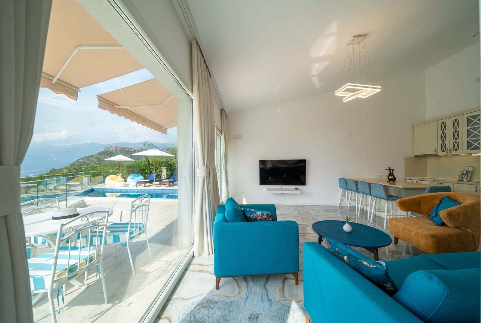 Living room with panoramic windows, a terrace, and a pool in the house, Blizikuće, Montenegro. Modern interior with bright furniture.