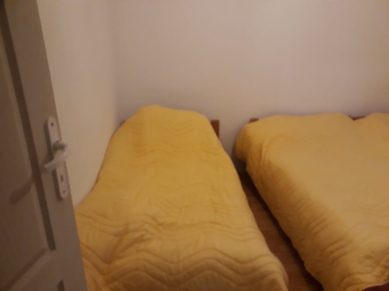 Bedroom with two single beds and yellow bedspreads in a house at the Žanjica resort, Montenegro.