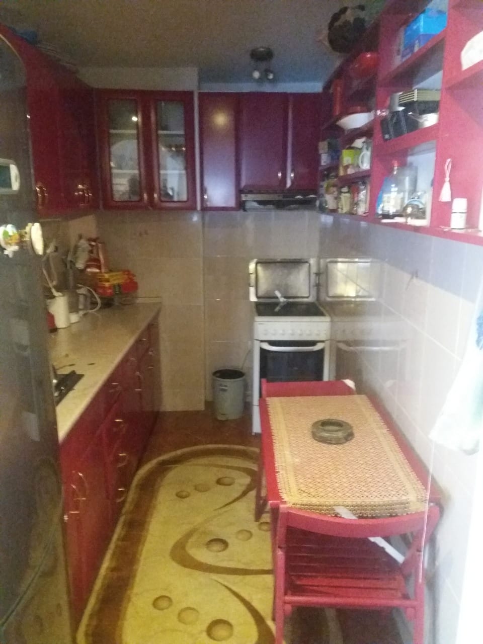 Kitchen with a red cabinet set, dining table, and stove in a house for sale in Muо, Montenegro.