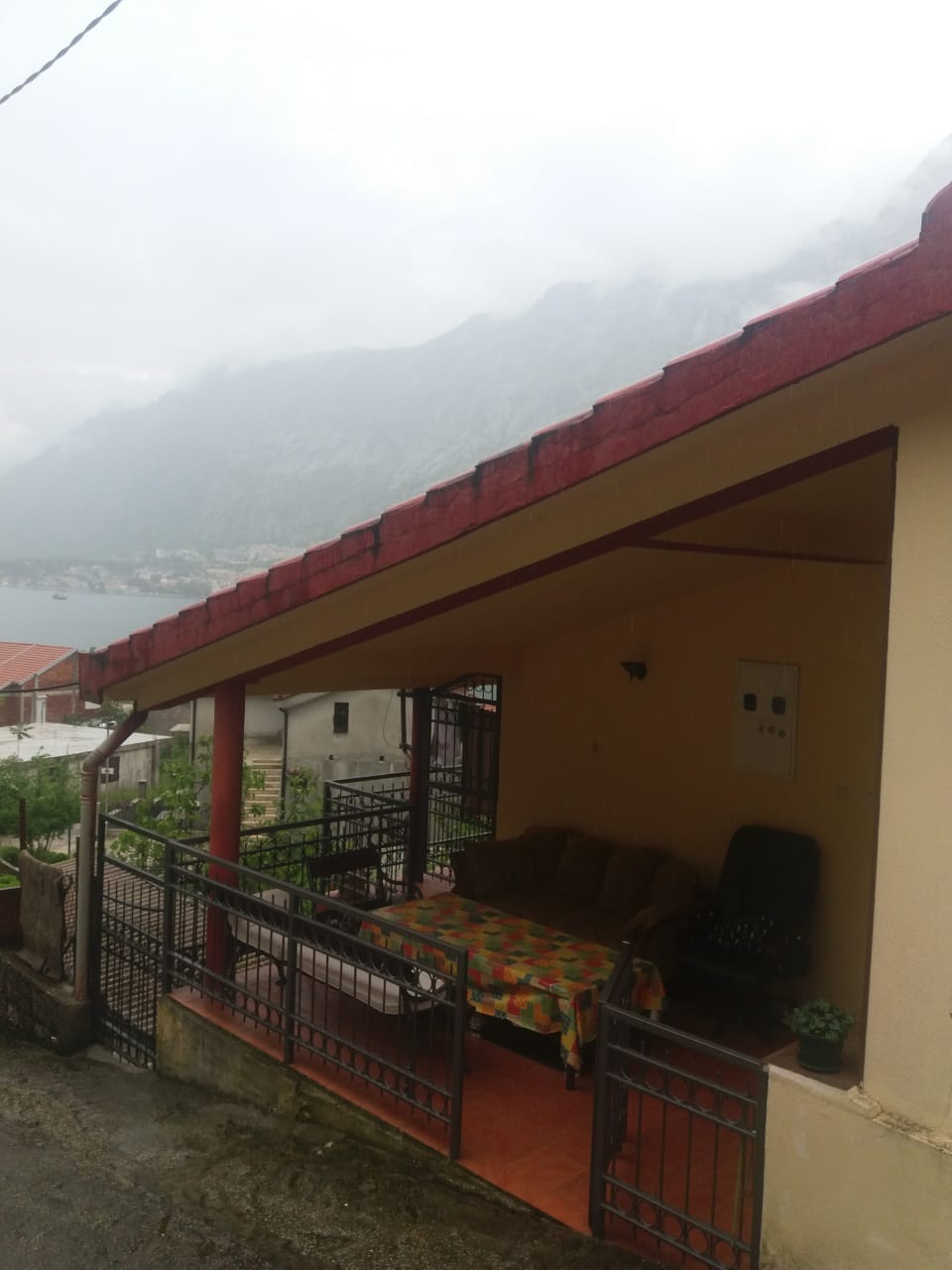 Covered terrace with furniture in a house, Muo, Montenegro: mountain and Bay of Kotor view from the balcony of a private house.