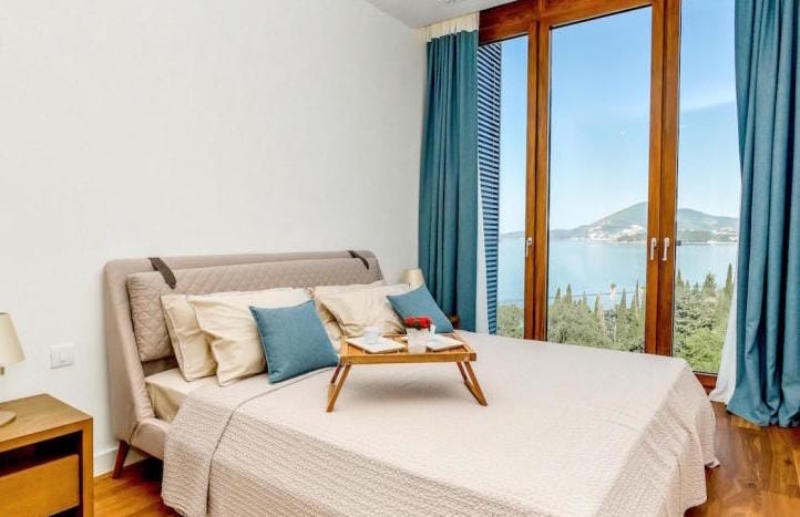 Bedroom in an apartment in Kamenovo, Montenegro: double bed, panoramic windows with sea and mountain views.