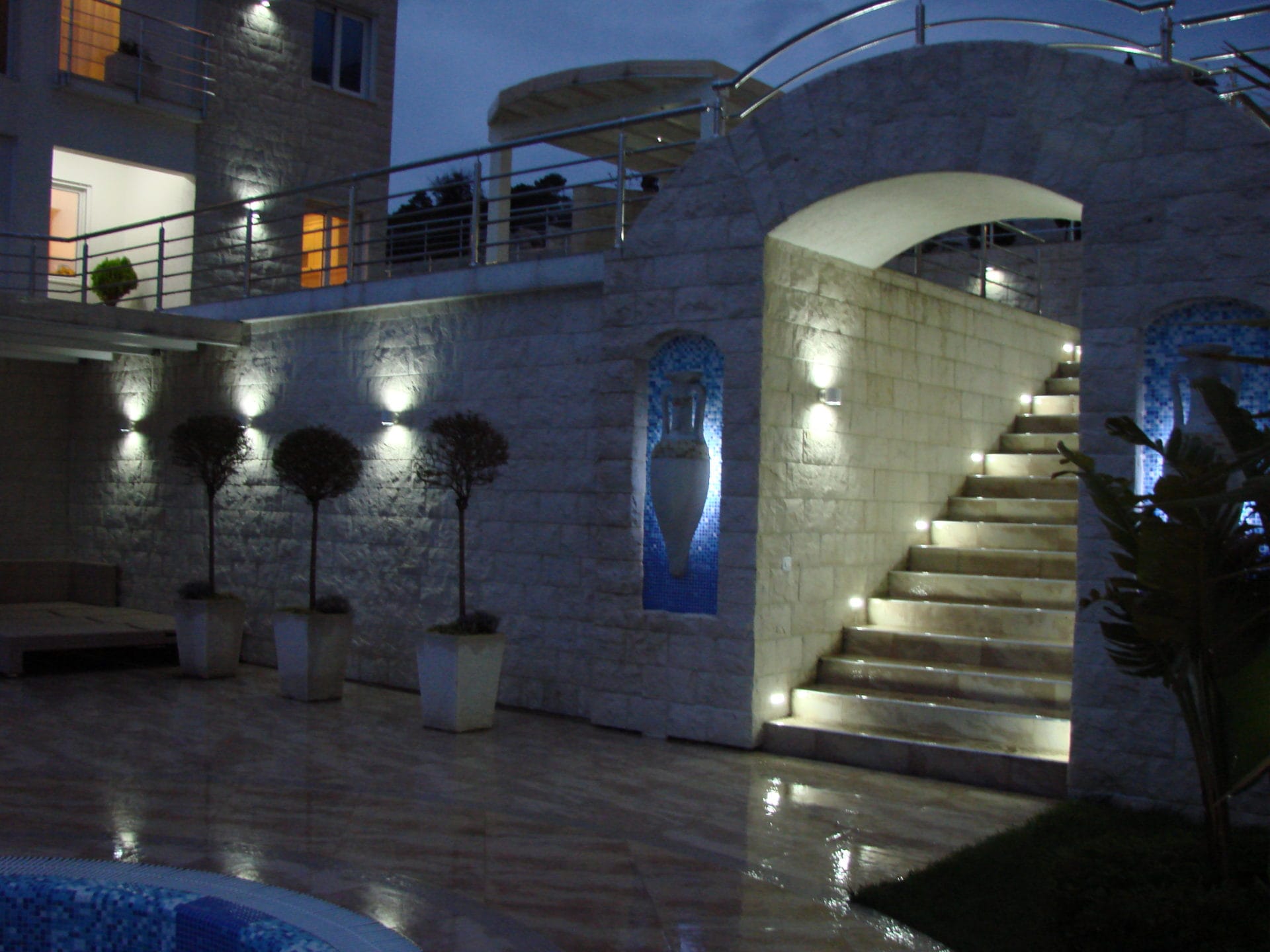 Evening lighting of the stone staircase and villa terrace in Dobra Voda, Montenegro, with a decorative niche and pool.