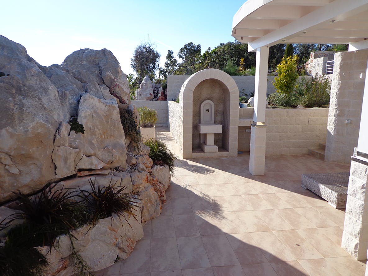 Villa terrace in Dobra Voda, Montenegro: stone finish, decorative fountain, and landscaped design with rocks.