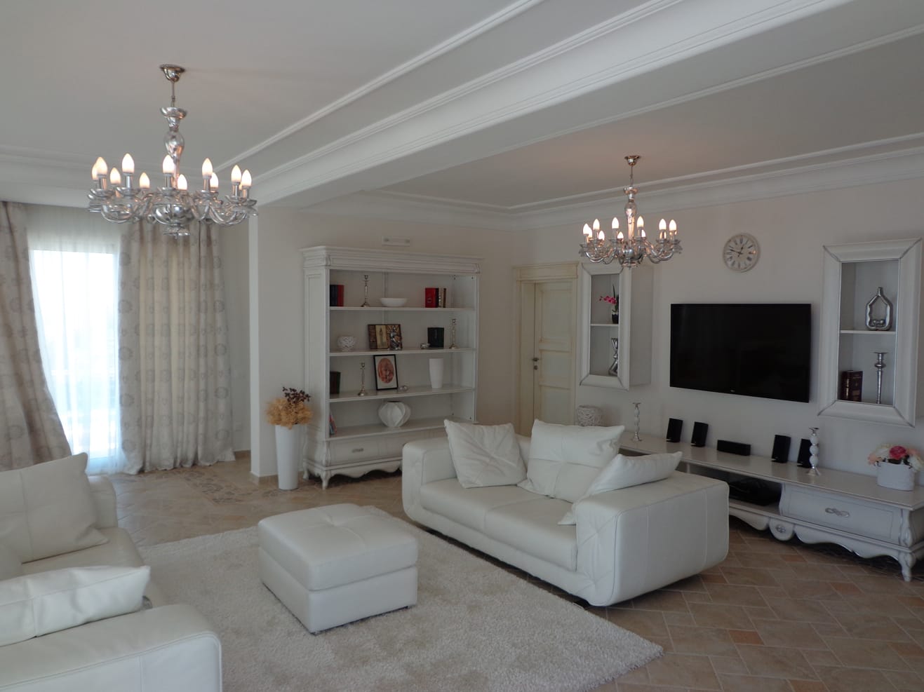 Bright living room with white leather furniture and crystal chandeliers in a villa in Dobra Voda, Montenegro.