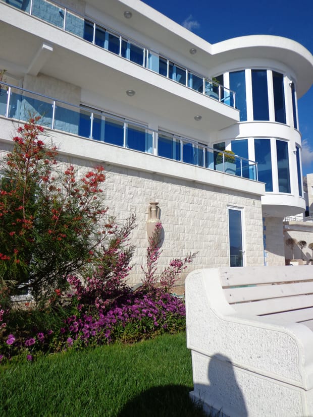 Modern villa with panoramic windows and terraces in Dobra Voda, Montenegro: front view and landscaped garden.