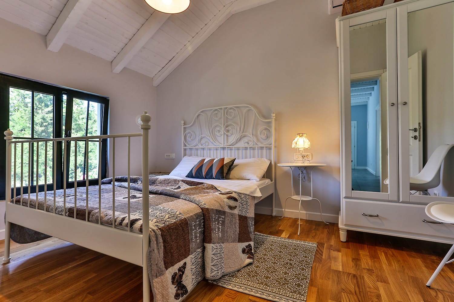 Cozy bedroom with a wrought-iron bed and wooden ceiling in a house for sale, Sutomore, Montenegro.