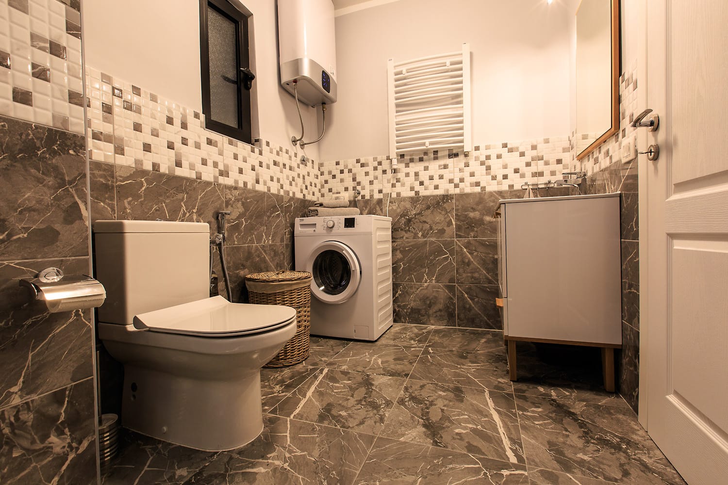 Bathroom in a house in Sutomore, Montenegro: marble tile finish, washing machine, and plumbing fixtures.