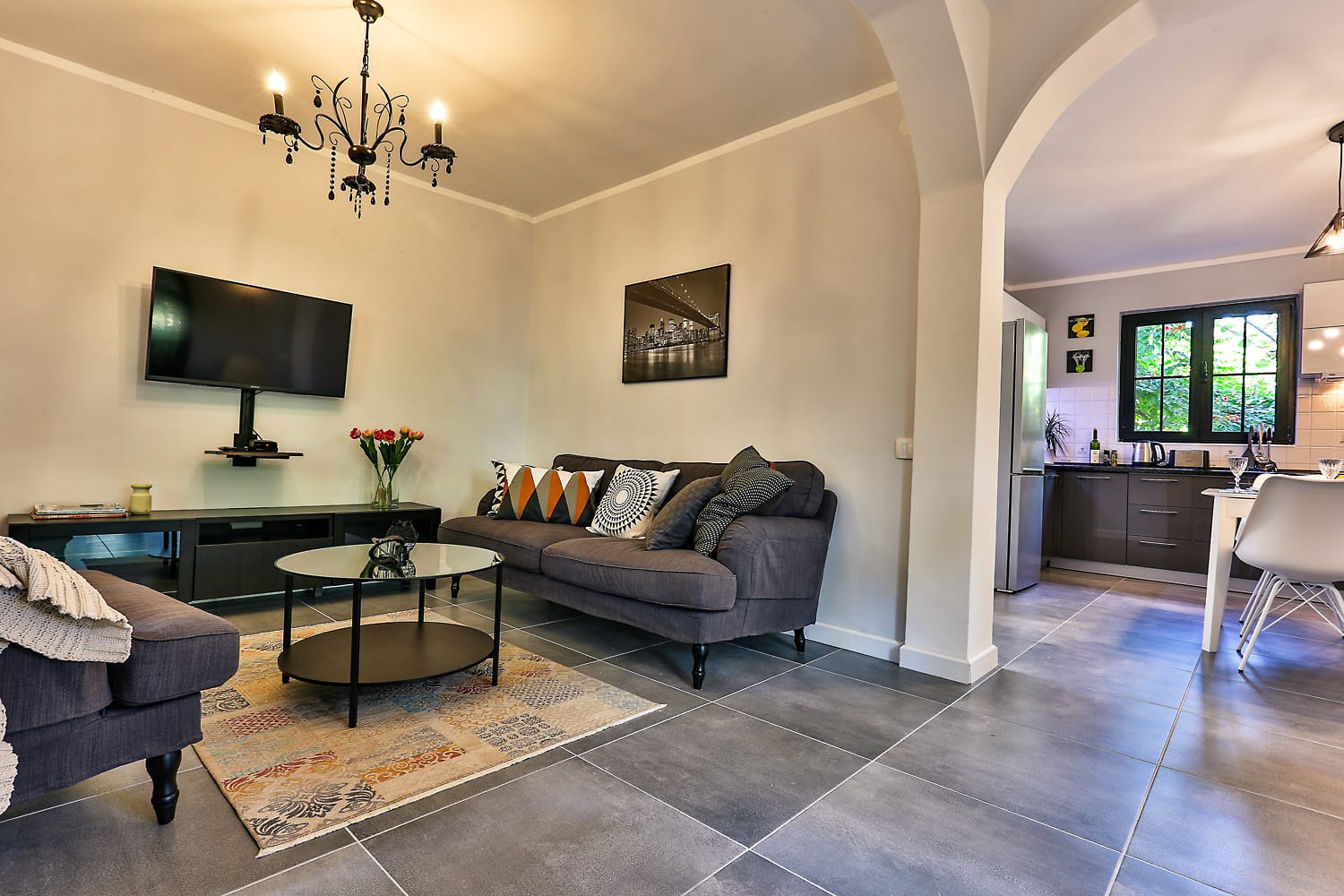 Living room with soft furniture and kitchen in a house, Sutomore, Montenegro: modern interior, tiled floor, and TV area.
