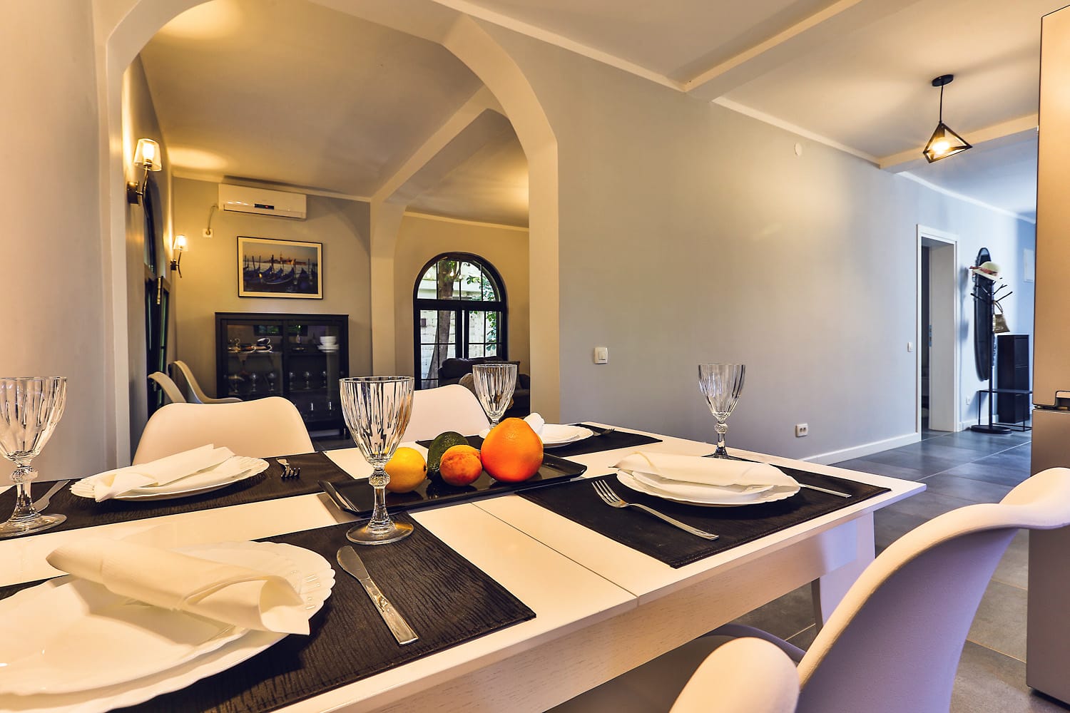 Dining table setting in a modern living room of a house in Sutomore, Montenegro, with arched openings and a bright design.