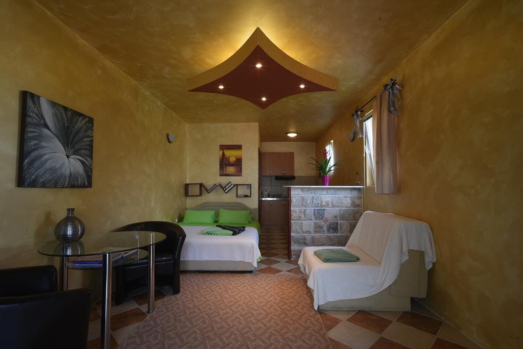 Living room with kitchen in a house in Muo, Montenegro: double bed, sofa, dining area, and stone finishes.
