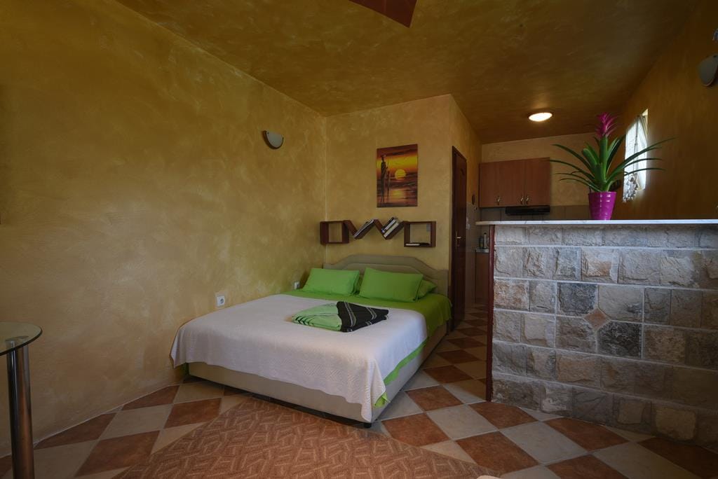 Bedroom interior in a house in Muo, Montenegro: double bed, stone bar counter, and tiled floor.