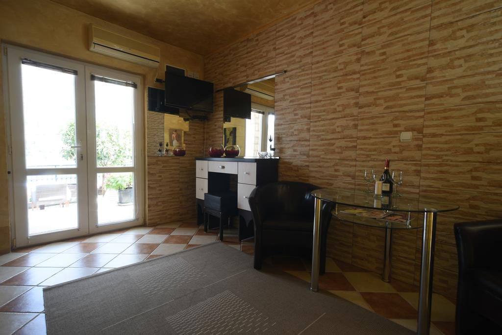 Living room with leather armchairs and a glass table in a house in Muo, Montenegro: tiled walls and access to the terrace.
