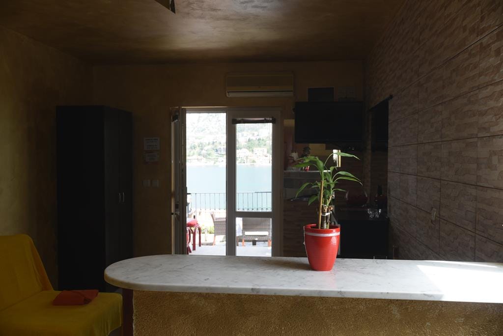 Living room with a bar counter and sea view in a house in Muo, Montenegro: interior with a yellow armchair and access to the terrace.