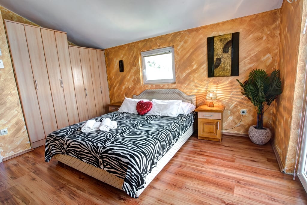 Bedroom in a house in Muo, Montenegro: double bed with zebra bedspread, wardrobe, decor, and laminate flooring.
