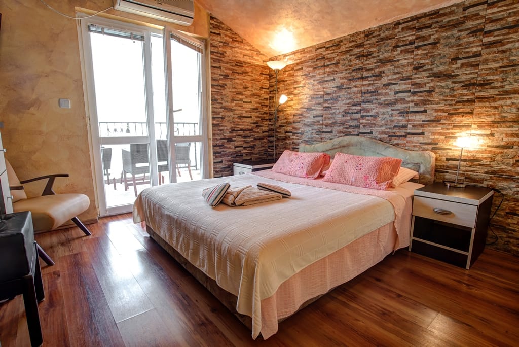 Bedroom with a double bed, stone wall finish, and access to the balcony in a house, Muo, Montenegro.