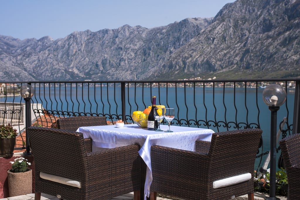 Terrace with wicker chairs and a view of Kotor Bay and the mountains, house in Muo, Montenegro.