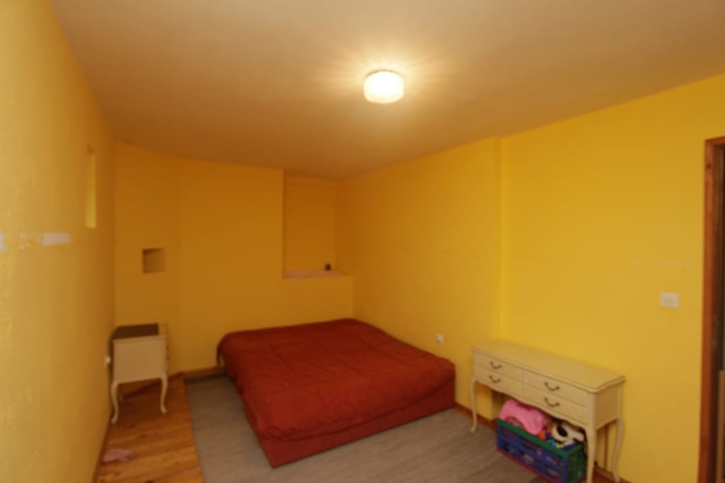 Bedroom with yellow walls, a double bed, and vintage furniture in a house for sale, Prčanj, Montenegro.