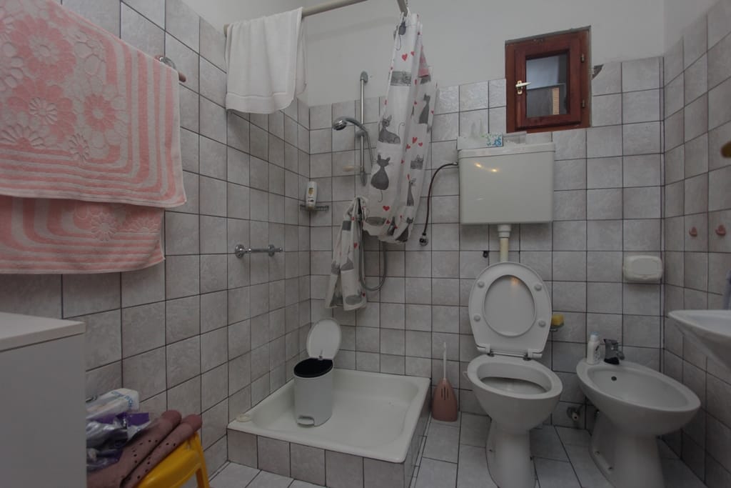 Bathroom in a house in Prčanj, Montenegro: light tiles, shower tray, toilet, bidet, and a small window.