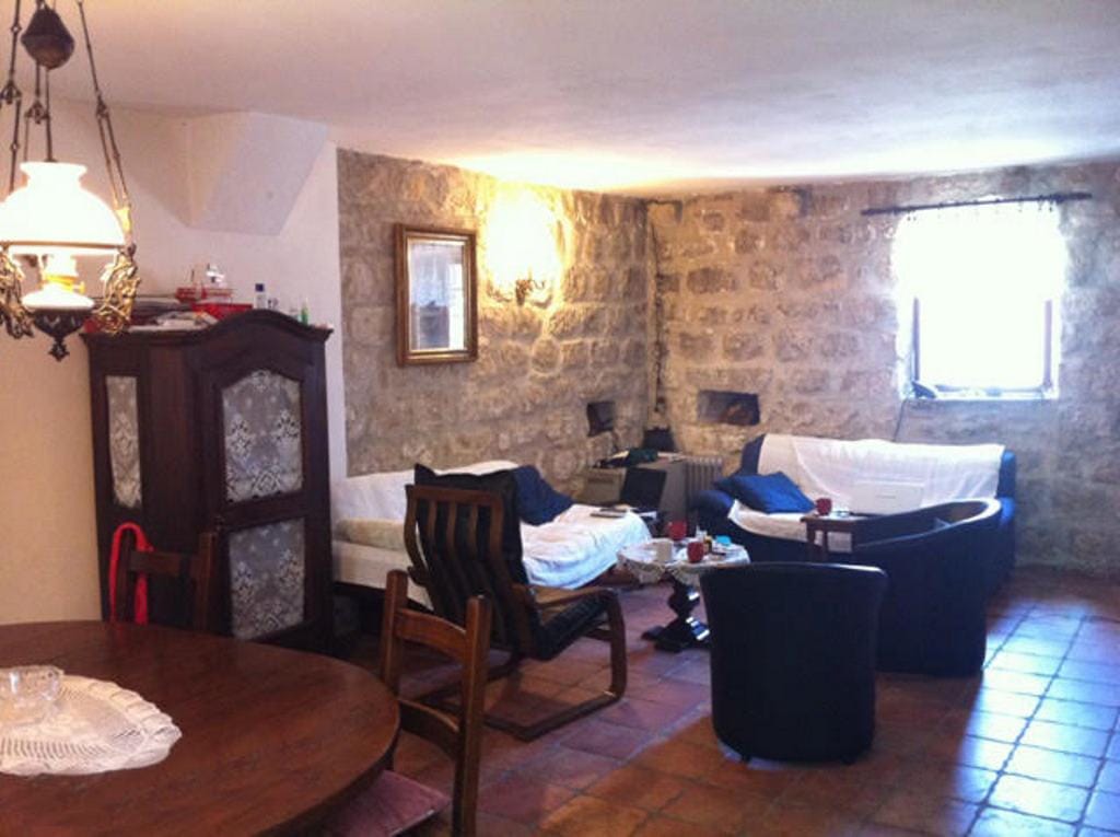 Living room in a stone house in Prčanj, Montenegro: interior with antique furniture, stone walls, and tiled floor.