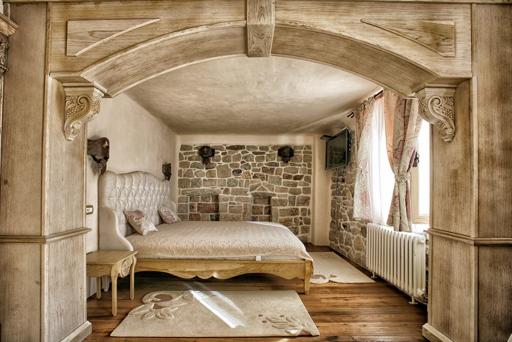Bedroom in a villa in Reževići, Montenegro: stone masonry, wooden arch, double bed, and vintage interior.