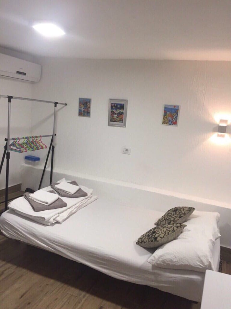 Bedroom in the Rafailovici mini-hotel, Montenegro: a bright room with a bed, air conditioner, and a standing clothes rack.