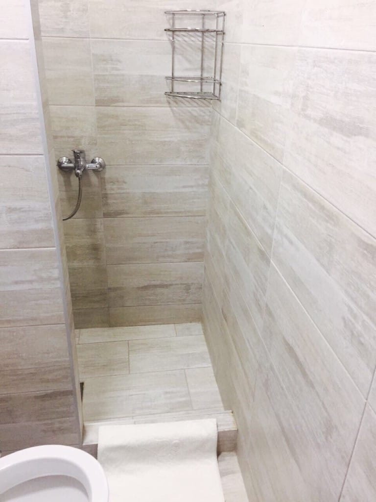 Shower cabin with beige tiles in the bathroom of a mini-hotel in Rafailovici, Montenegro.