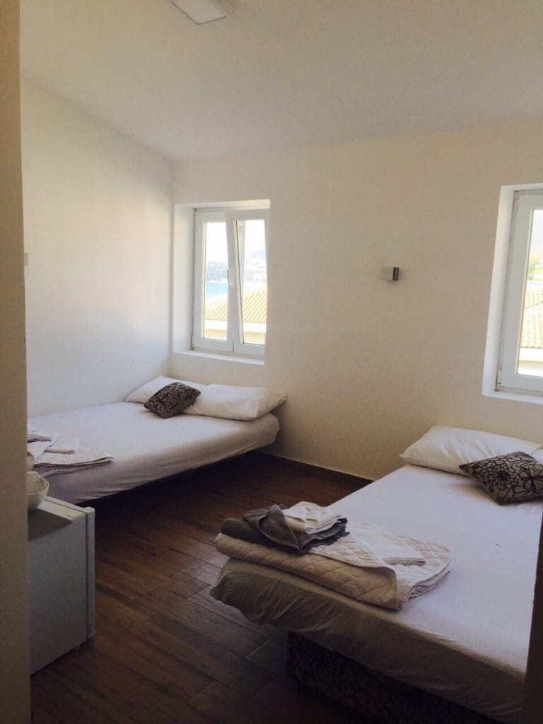 Bedroom in the Rafailovici mini-hotel, Montenegro: two beds, bright interior, wooden floor, and sea view from the window.