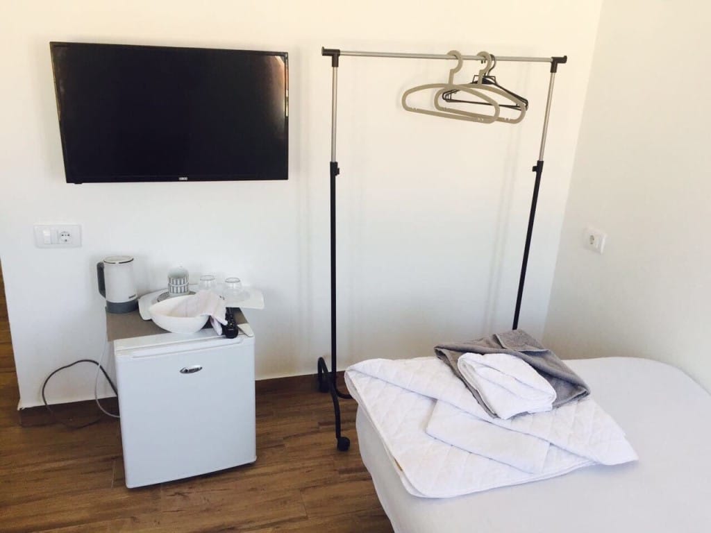 Bedroom interior in a hotel in Rafailovici, Montenegro: bed, TV, mini fridge, kettle, and a floor clothes rack.