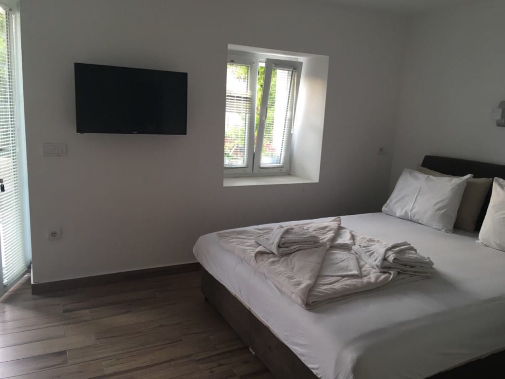 Bedroom in the Rafailovici mini-hotel, Montenegro: double bed, wall-mounted TV, and light interior finishes.