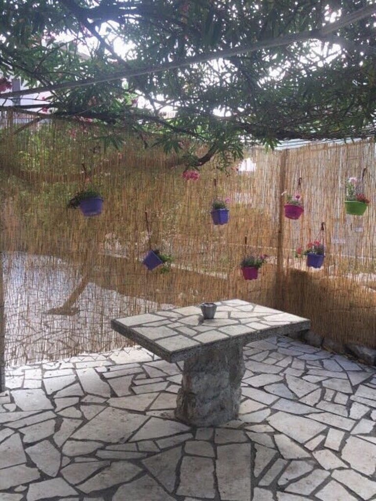 Cozy terrace with a stone table and hanging flowers in a mini-hotel, Rafailovici, Montenegro.