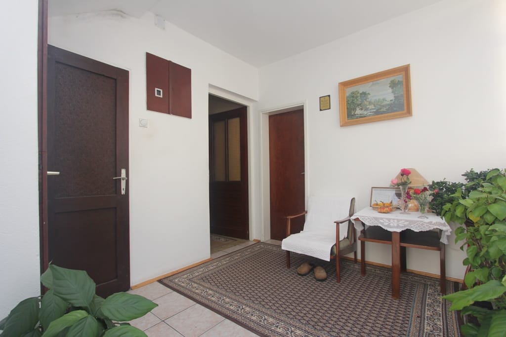 Bright hallway in a house, Orahovac, Montenegro: rug, wooden doors, armchair, and houseplants in the interior.