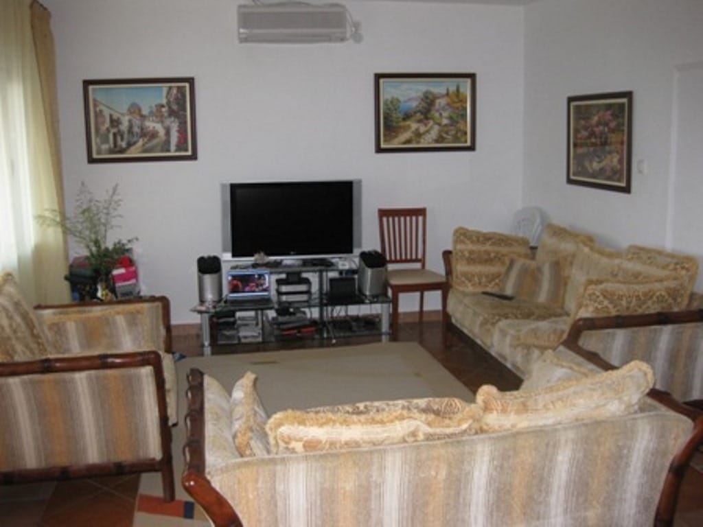 Living room in a house in Sutomore, Montenegro: upholstered furniture, TV, wall art, and air conditioning in the interior.