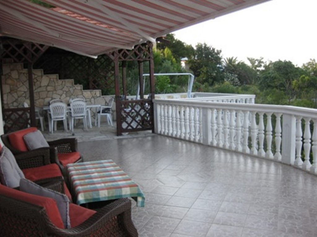 Spacious terrace with wicker furniture and an awning in a house, Sutomore, Montenegro: view of the garden and stone finishes.