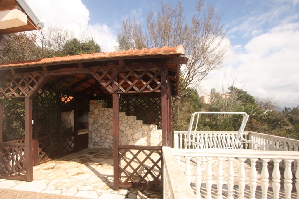 Wooden gazebo with a stone barbecue and swings on the terrace of a house in Sutomore, Montenegro.