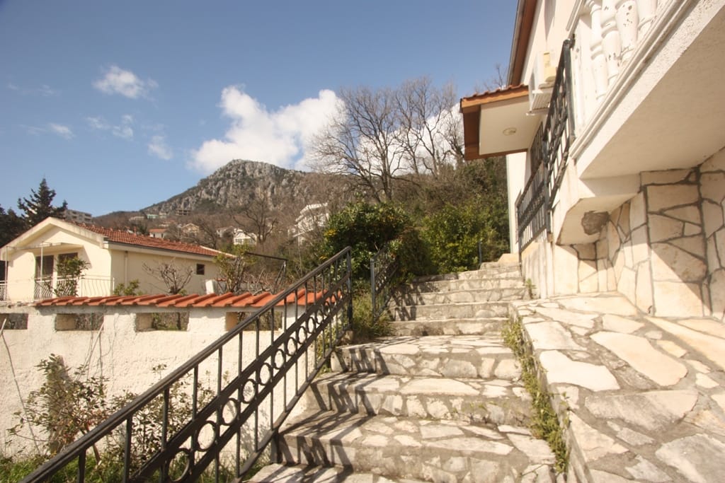 Stone staircase and house facade in Sutomore, Montenegro, with a view of the mountains and the adjacent plot area.