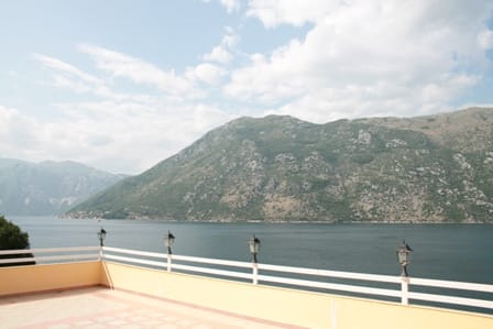Panoramic view from the hotel terrace in Stoliv, Montenegro: an open terrace with a white railing and a view of the Bay of Kotor.
