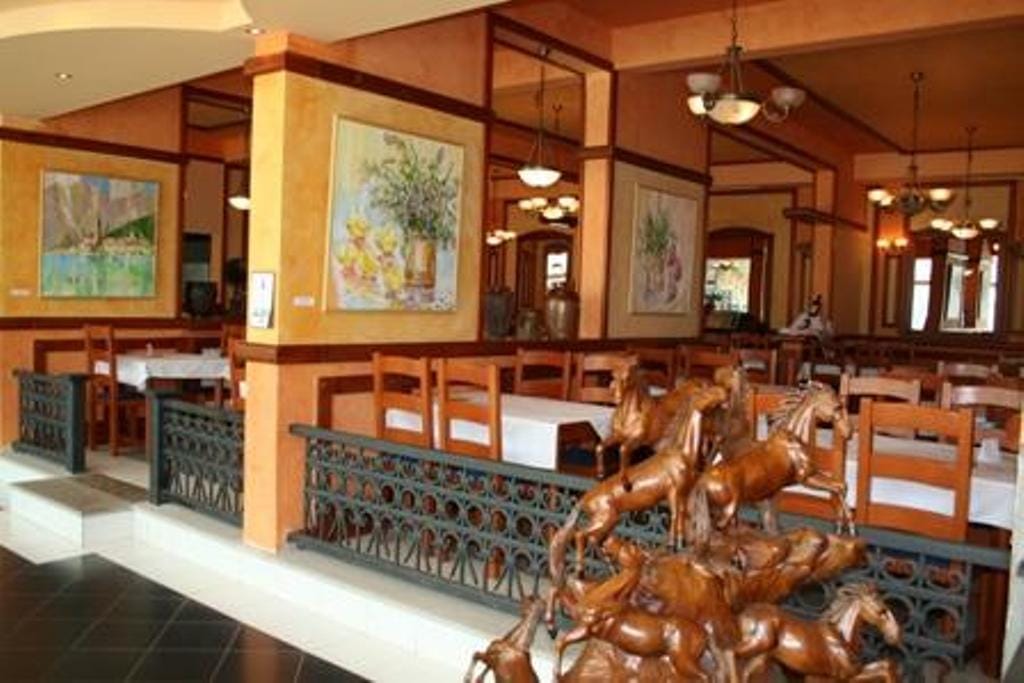 Hotel restaurant interior in Stoliv, Montenegro: wooden furniture, wrought-iron railings, and classic-style decor.