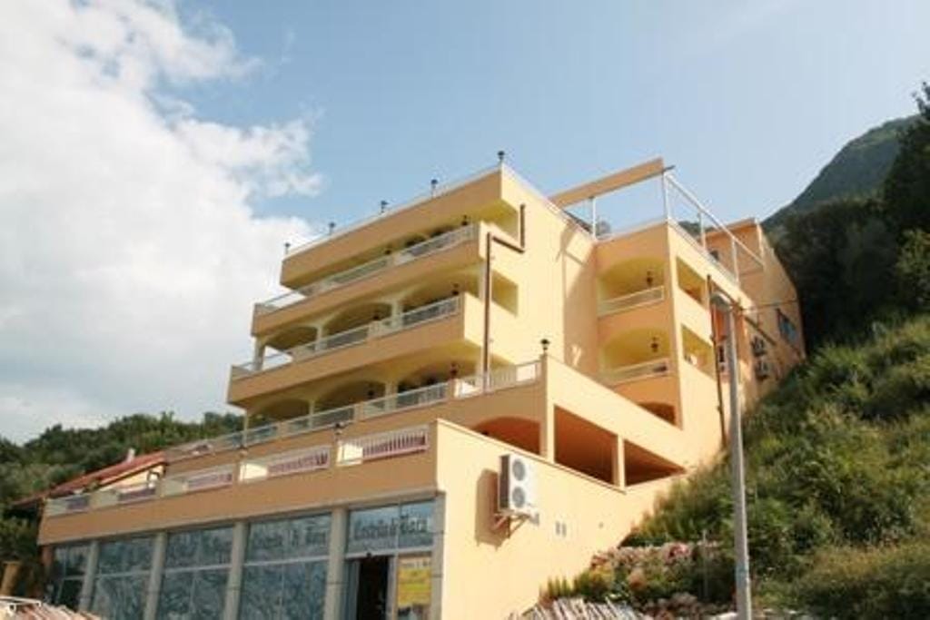 Hotel facade in Stoliv, Montenegro: a multi-story building with terraces and panoramic views of the mountains and sea.