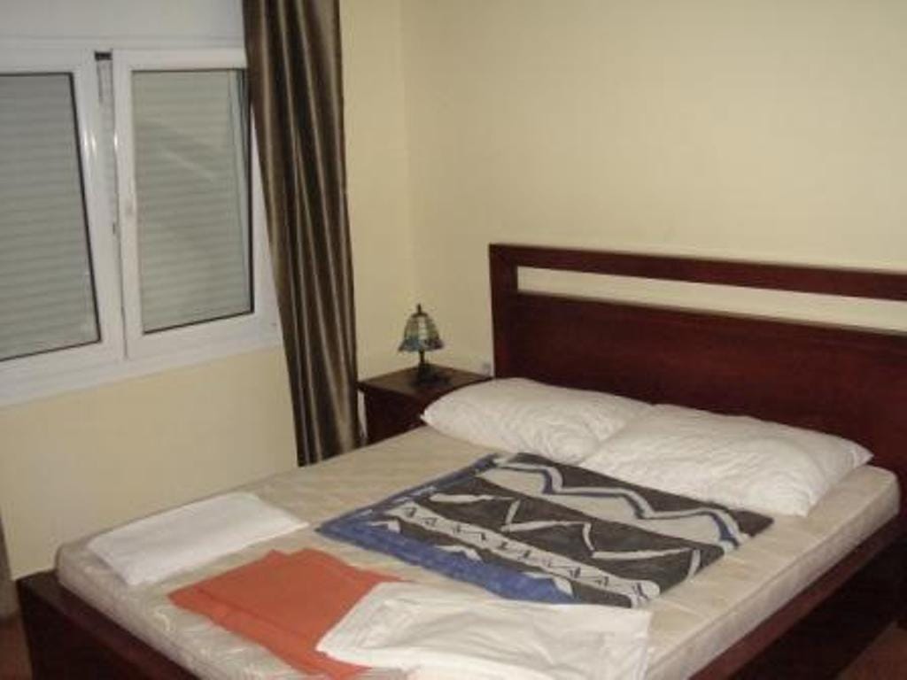 Bedroom with a double bed at the Stoliv hotel, Montenegro: dark wooden furniture, light walls, and a window with blinds.