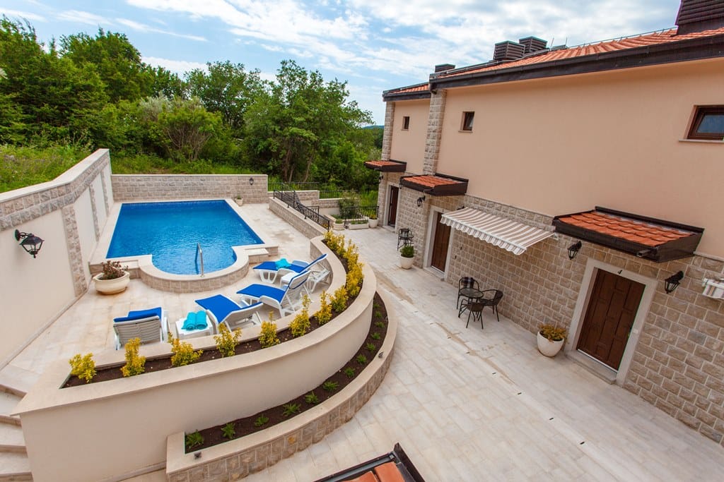 Pool and lounge area with sun loungers by the villa in Kamenovo, Montenegro: stone facade and terrace finishes.