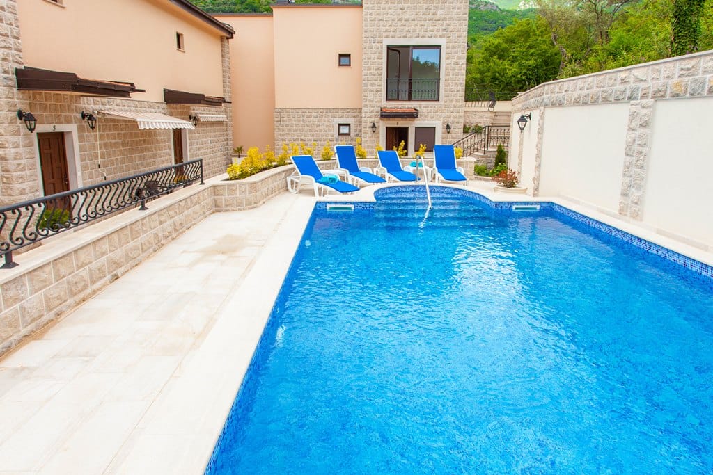 An outdoor pool with sun loungers by stone apartments in Kamenovo, Montenegro.