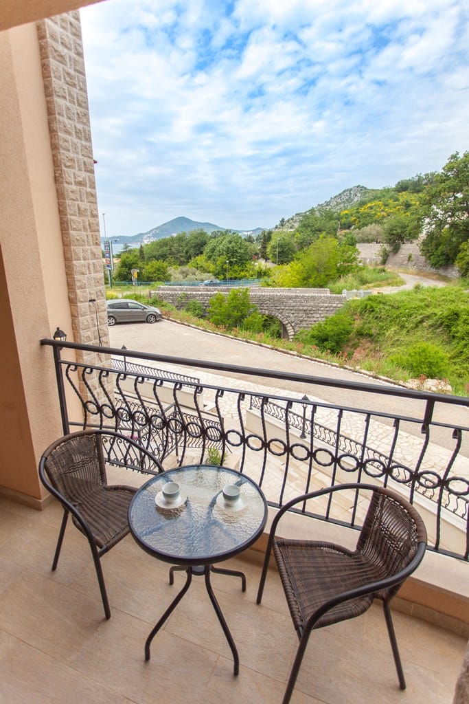 Balcony with wicker chairs and a view of the mountains and the sea in an apartment, Kamenovo, Montenegro.