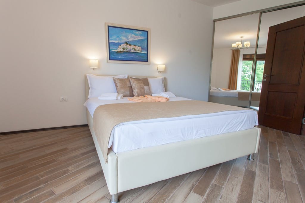 Cozy bedroom with a double bed and mirrored wardrobe in an apartment in Kamenovo, Montenegro.